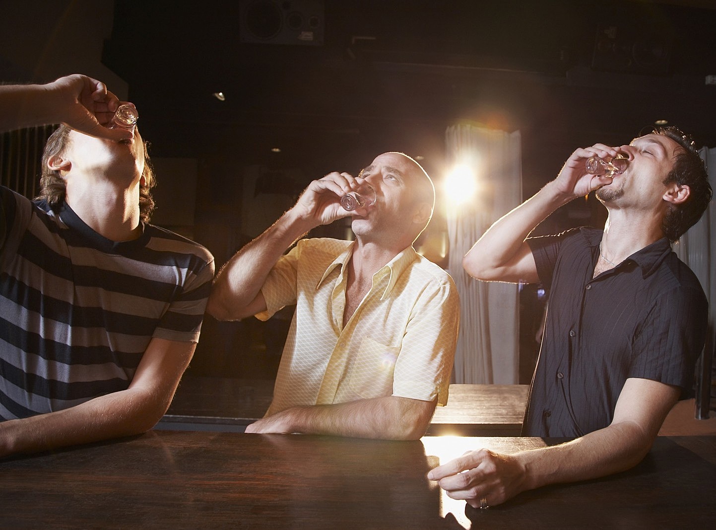 Hispanic men drinking shots at bar